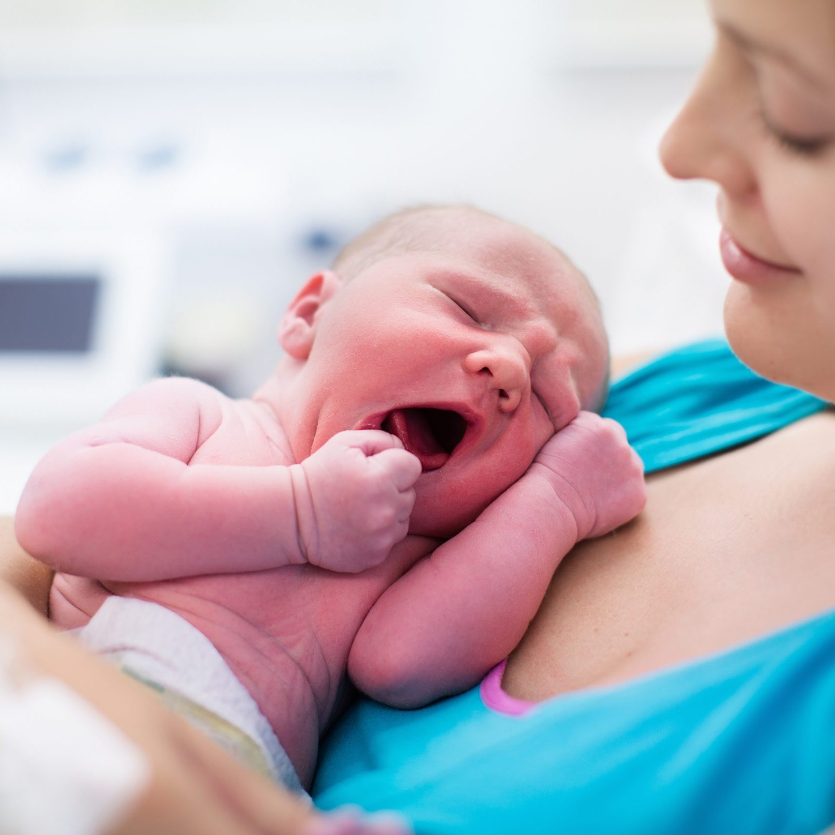 Mother giving birth to a baby. Newborn baby in delivery room. Mom holding her new born child after labor. Female pregnant patient in a modern hospital. Parent and infant first moments of bonding.